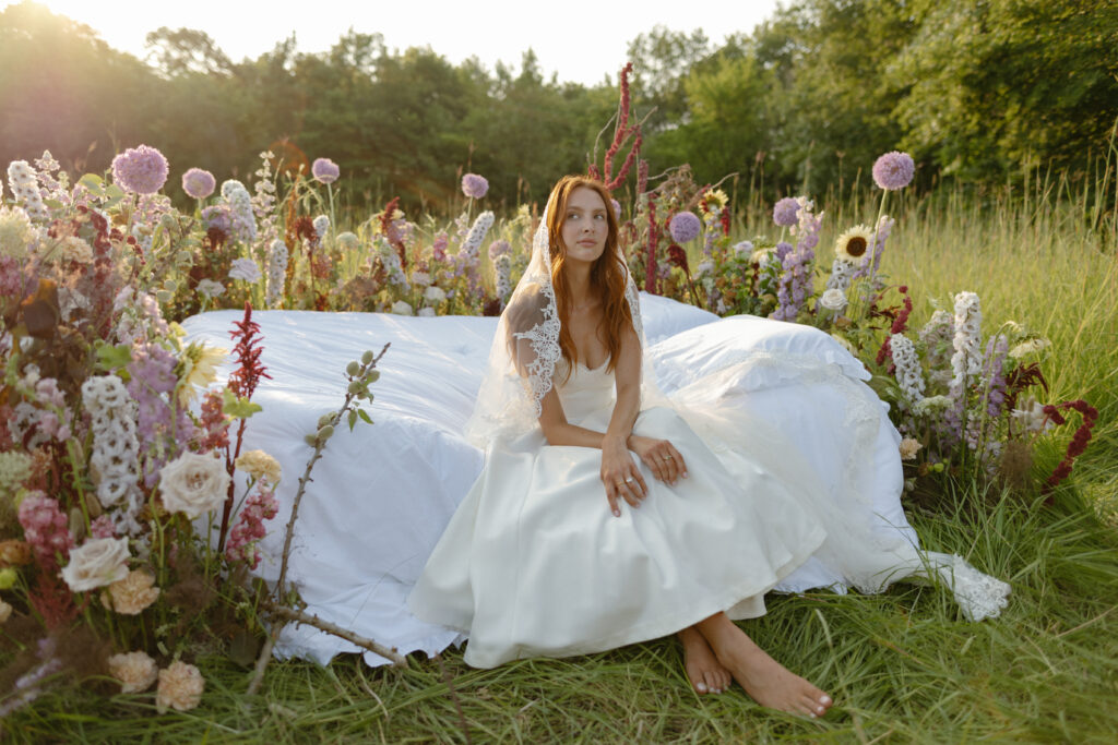 A serene bride, Ella, standing barefoot in a meadow with wildflowers, embodying tips and inspiration to transform your elopement morning into a magical, intentional experience.