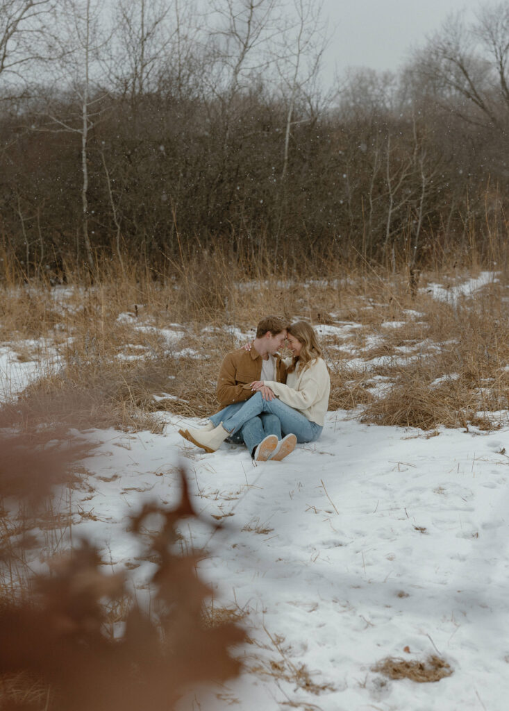 Couple sitting together in the snow during a Rice Creek winter engagement