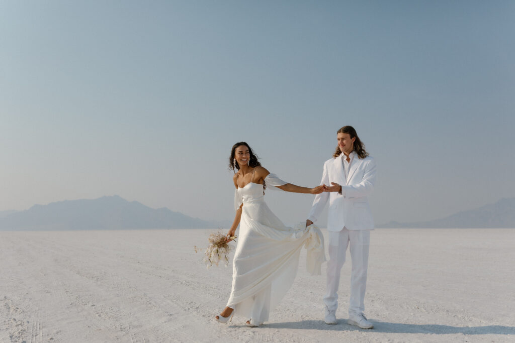 Bride and groom walking across the Bonneville Salt Flats during their ethereal elopement