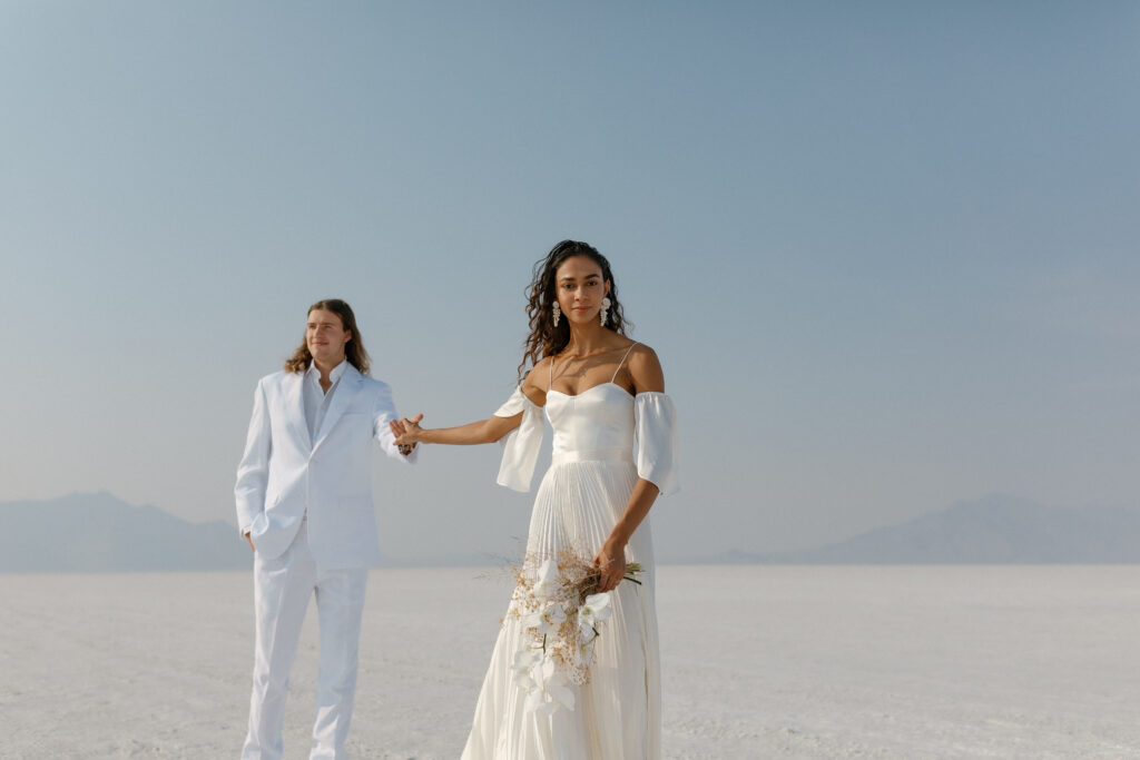 Bride and groom walking across the Bonneville Salt Flats during their ethereal elopement