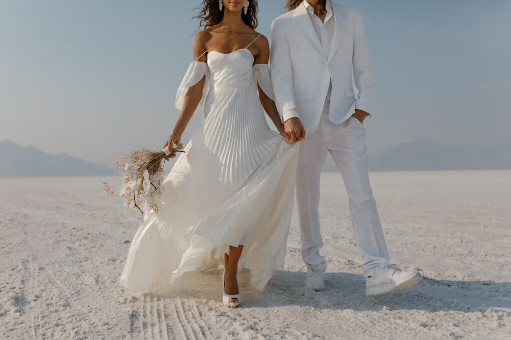 Bride and groom walking across the Bonneville Salt Flats during their ethereal elopement