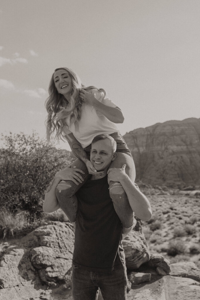 Playful engagement portraits on lava rock with mountain views in Snow Canyon State Park