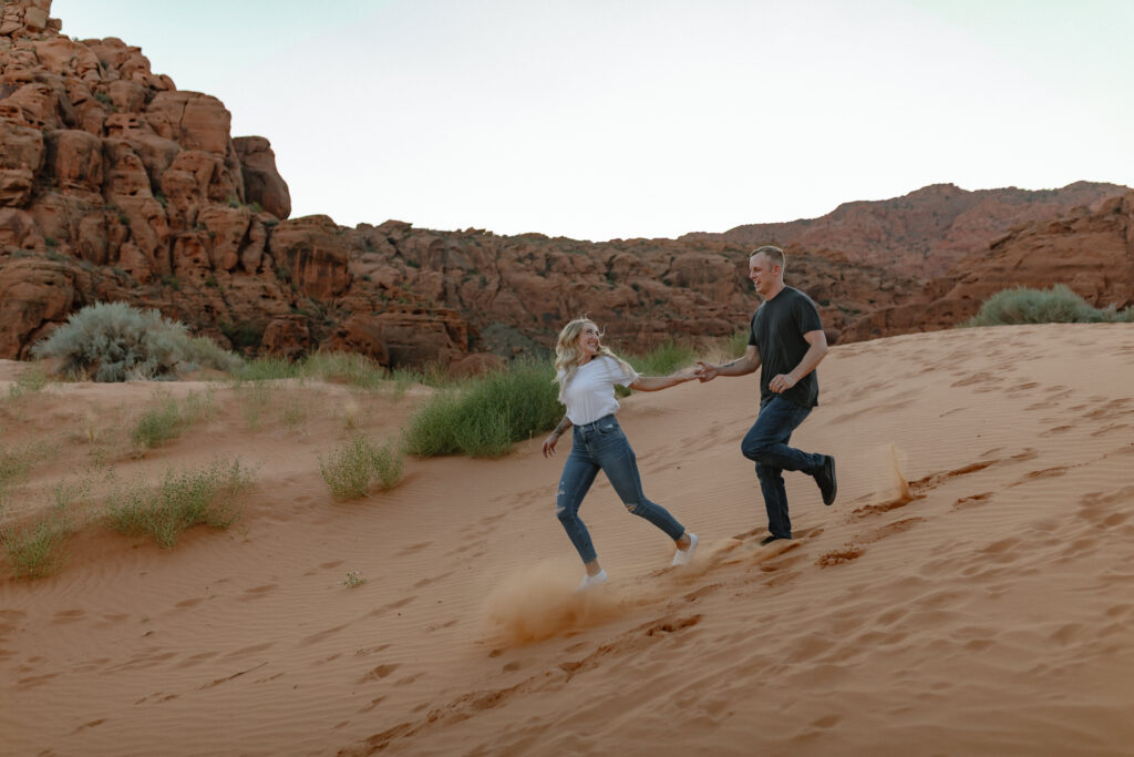 Playful engagement portraits on lava rock with mountain views in Snow Canyon State Park