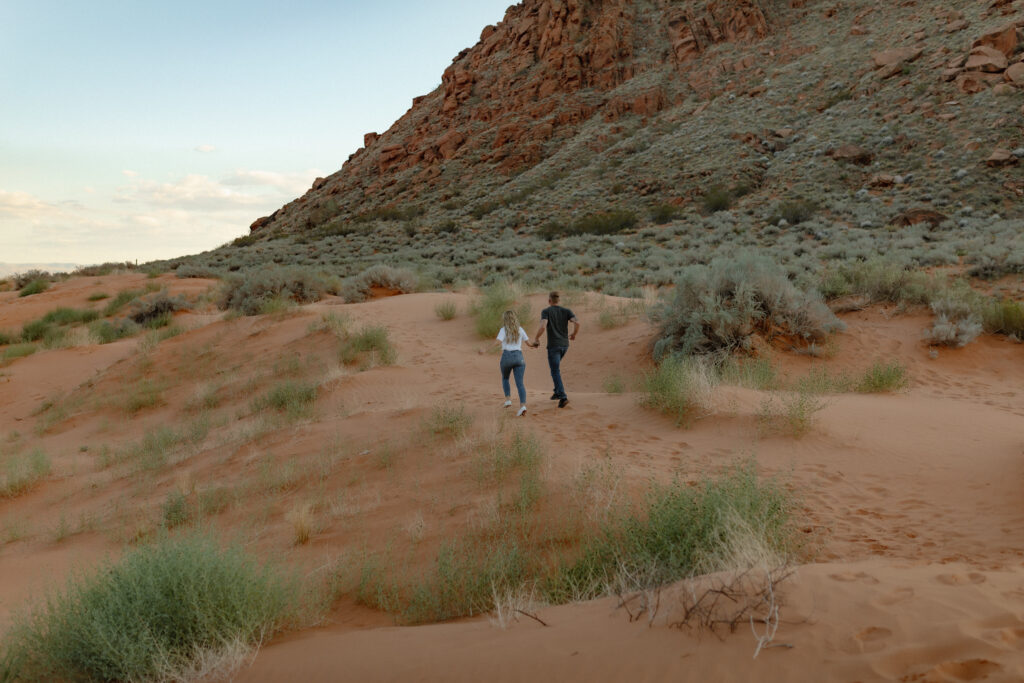 Playful engagement portraits on lava rock with mountain views in Snow Canyon State Park