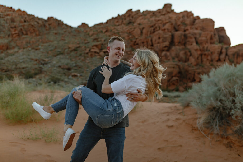 Playful engagement portraits on lava rock with mountain views in Snow Canyon State Park