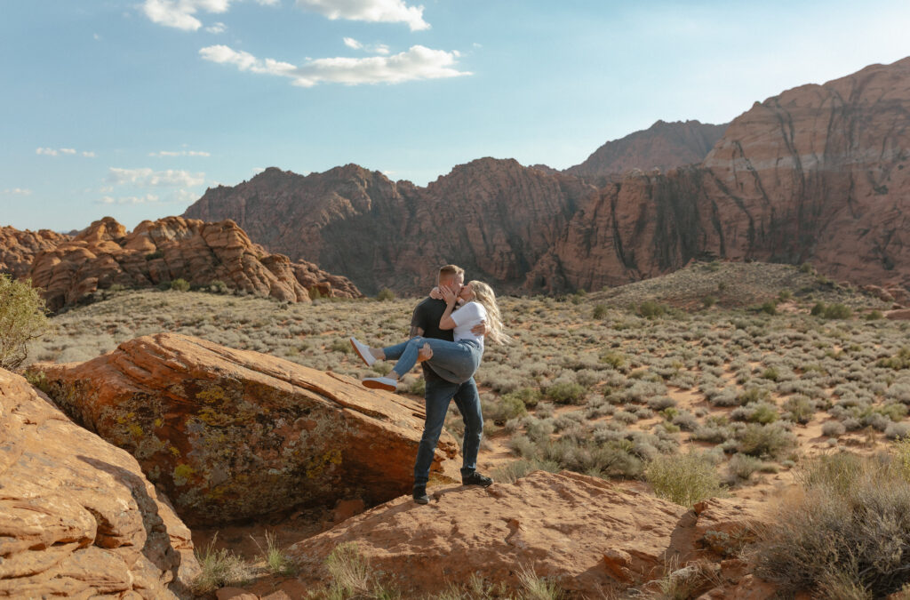 Playful engagement portraits on lava rock with mountain views in Snow Canyon State Park