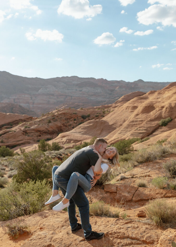 Playful engagement portraits on lava rock with mountain views in Snow Canyon State Park